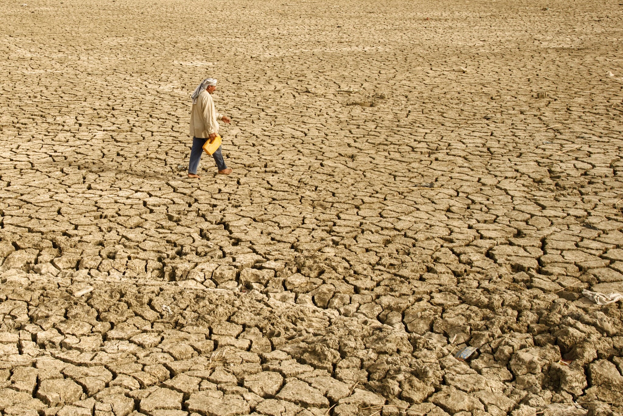 climate change in Iraq; drought and arid conditions in iraq; woman walking on arid land in Iraq