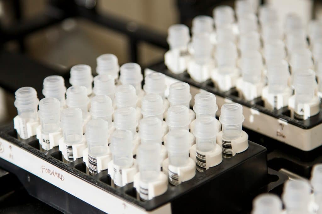 An automated test tube filler fills a group of plastic test tubes.