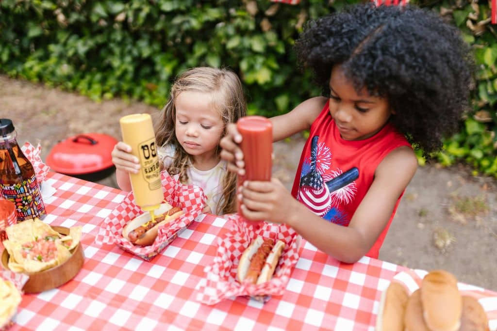 Two girls eating hotdogs outdoors